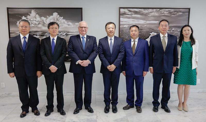 Foto colorida na horizontal de grupo de pessoas lado a lado. No centro está o ministro Edson Fachin, um senhor branco de cabelos brancos. As outras seis pessoas são chinesas, entre elas há apenas uma mulher, no canto direito da foto. Ao fundo deles há dois quadros com paisagens de rios.