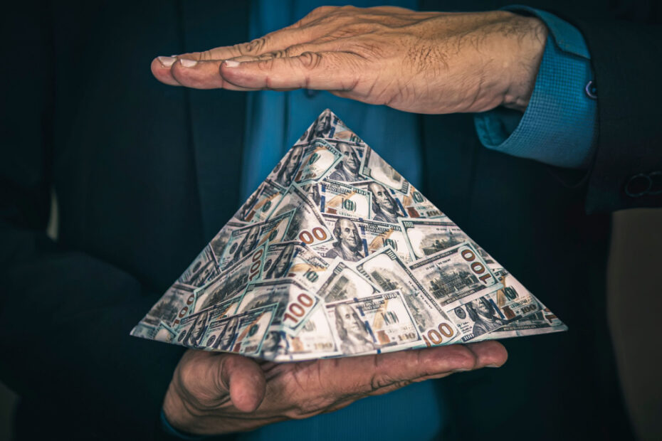 homem segura com duas mãos uma piramide de dinheiro