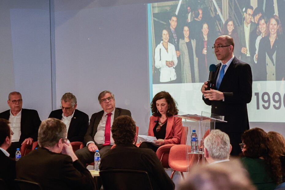 Palco com uma pessoa em pé e outras sentadas