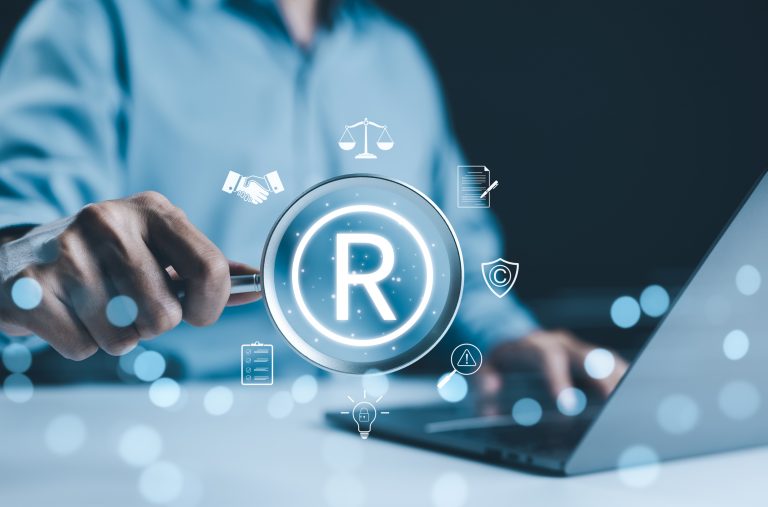 Pessoa digita num laptop e há ícones de marca registrada por cima