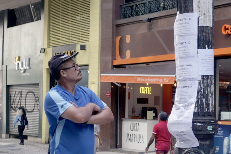 homem observa anúncios de empregos em um poste